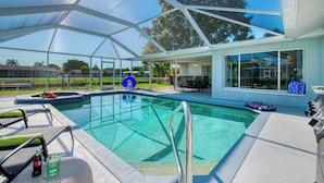 A covered outdoor swimming pool with a clear view of the surrounding area, including a patio with seating and a table.