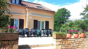 A building with a tiled roof, a stone staircase leading to a porch, and outdoor seating with plastic chairs. - Gite for 15 people Le Canebal right, wifi heated pool to share (Sarlat-la-Canéda)