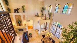 A spacious living area with a fireplace, a dining table, and multiple potted plants.