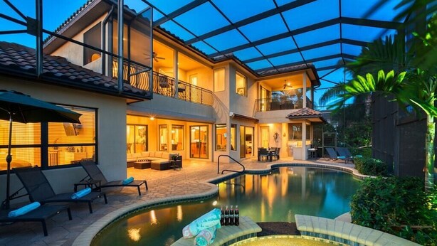 A two-story house with a swimming pool, outdoor seating, and a covered patio area.