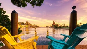 A wooden deck with two Adirondack chairs, each with a bottle of Corona beer.