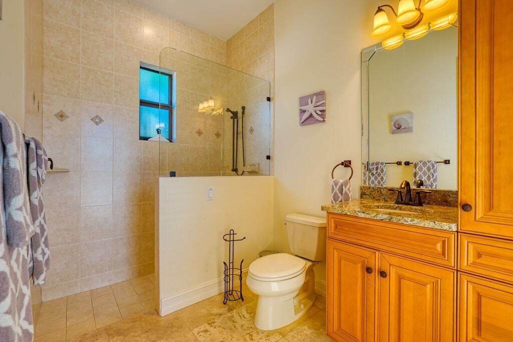 Une salle de bain avec une douche en verre, des toilettes et des meubles en bois.