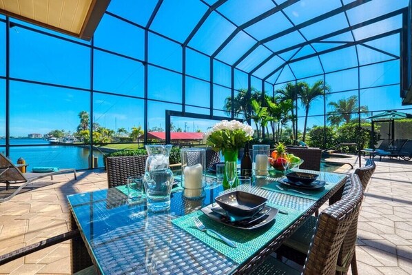 Enjoy a meal with a view of the water and palm trees from this sheltered outdoor dining area.