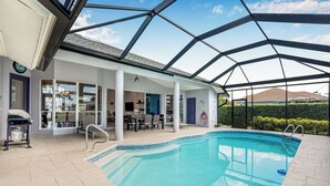 Una piscina scoperta coperta con zona solarium, barbecue e vista sul paesaggio circostante.