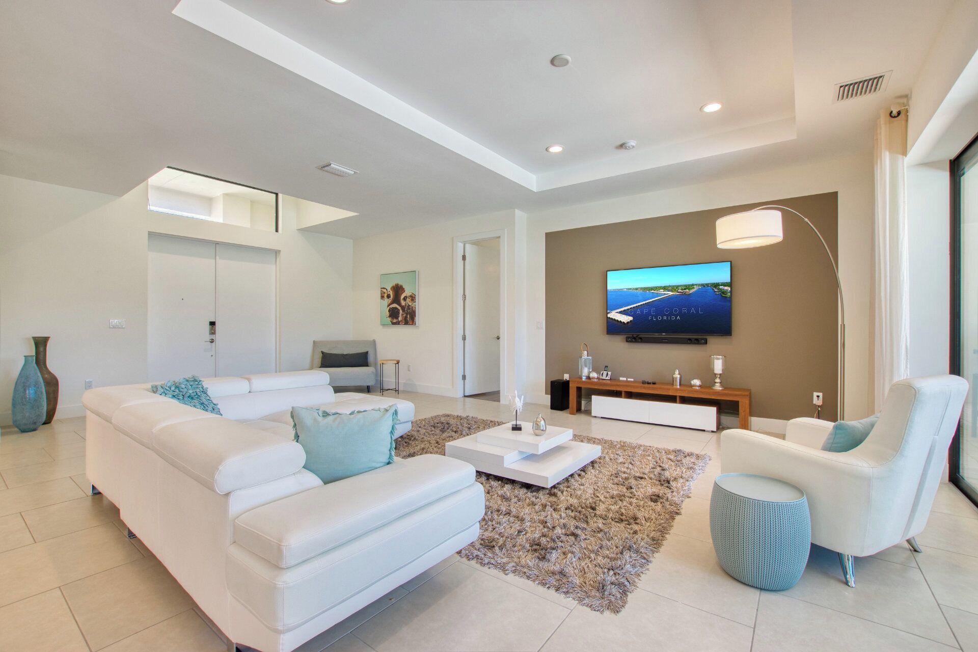 Ein modernes Wohnzimmer mit einem weißen Sofa, einem Couchtisch, einem Fernseher und einer Lampe.