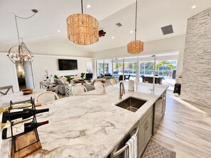 A modern kitchen with a marble countertop, wine rack, and pendant lighting.