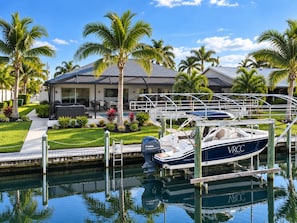 Un puerto deportivo con un barco amarrado, una piscina y una casa con porche cubierto.