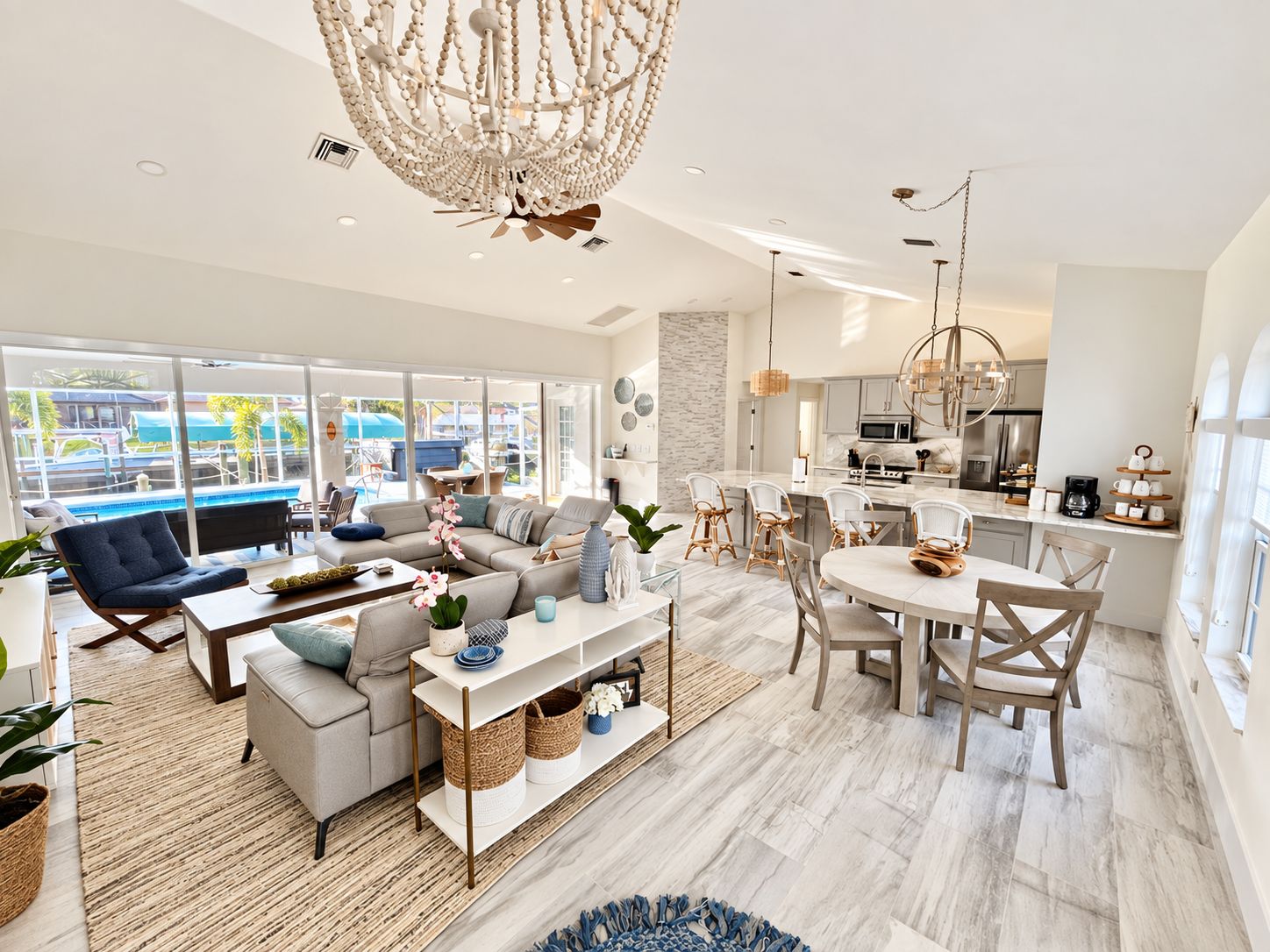 A modern living room with a large window, a dining area, and a kitchen with stainless steel appliances.