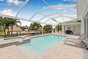 A covered outdoor swimming pool with lounge chairs and a boat docked nearby.