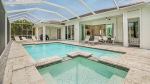 A pool area with a glass-enclosed patio, lounge chairs, and a dining area with a table and chairs. - VRCC Villa Nouveau - 4 bedrooms, pool and spa (Cape Coral)