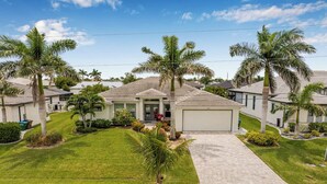 A residential neighborhood with single-family homes, each with a garage, surrounded by well-maintained lawns and palm trees.