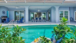 A poolside area with a covered patio, a grill, and outdoor seating. - VRCC Villa Sansibar (Cape Coral)