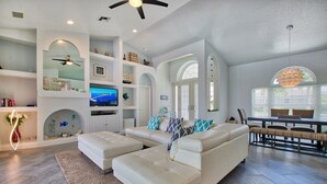 A spacious living room with a sectional sofa, a flat-screen TV, and a dining area with a table and chairs. - VRCC Villa Sansibar (Cape Coral)