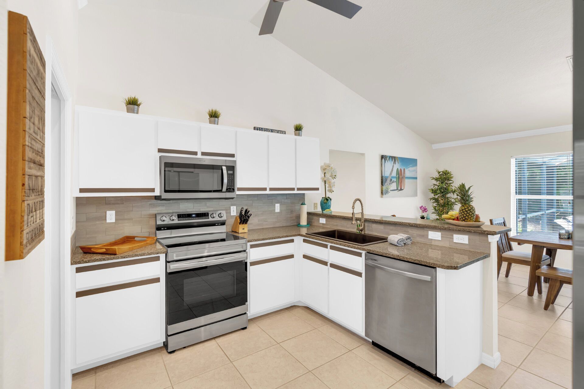 A modern kitchen with white cabinetry, stainless steel appliances, a granite countertop, and a built-in dishwasher.