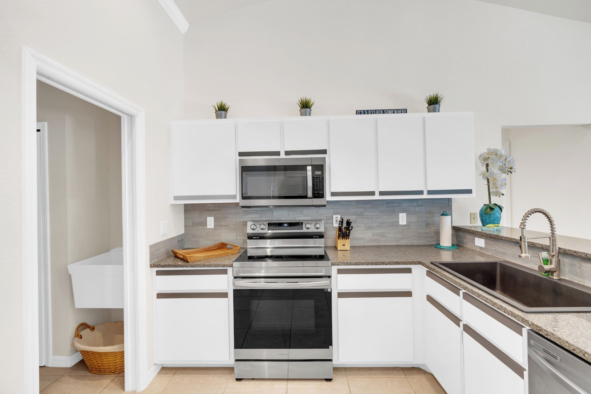 A modern kitchen with white cabinetry, a stainless steel range, a microwave, and a sink.