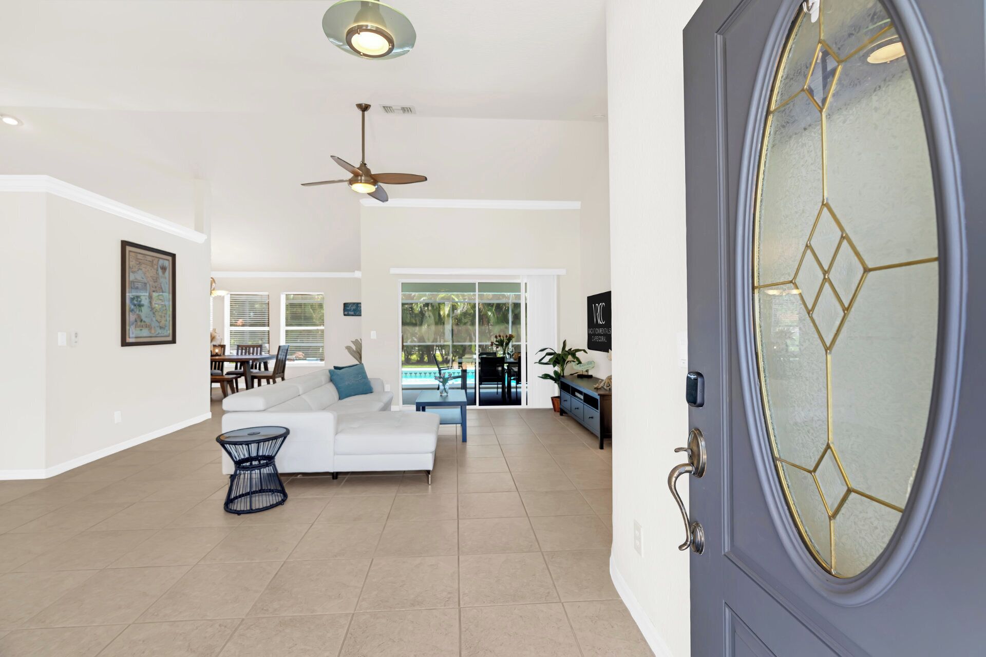 A spacious living area with a white sofa, a dining table, and a ceiling fan.