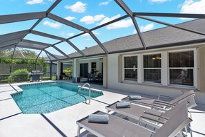 Une piscine extérieure couverte, dotée de chaises longues et d’un espace patio.