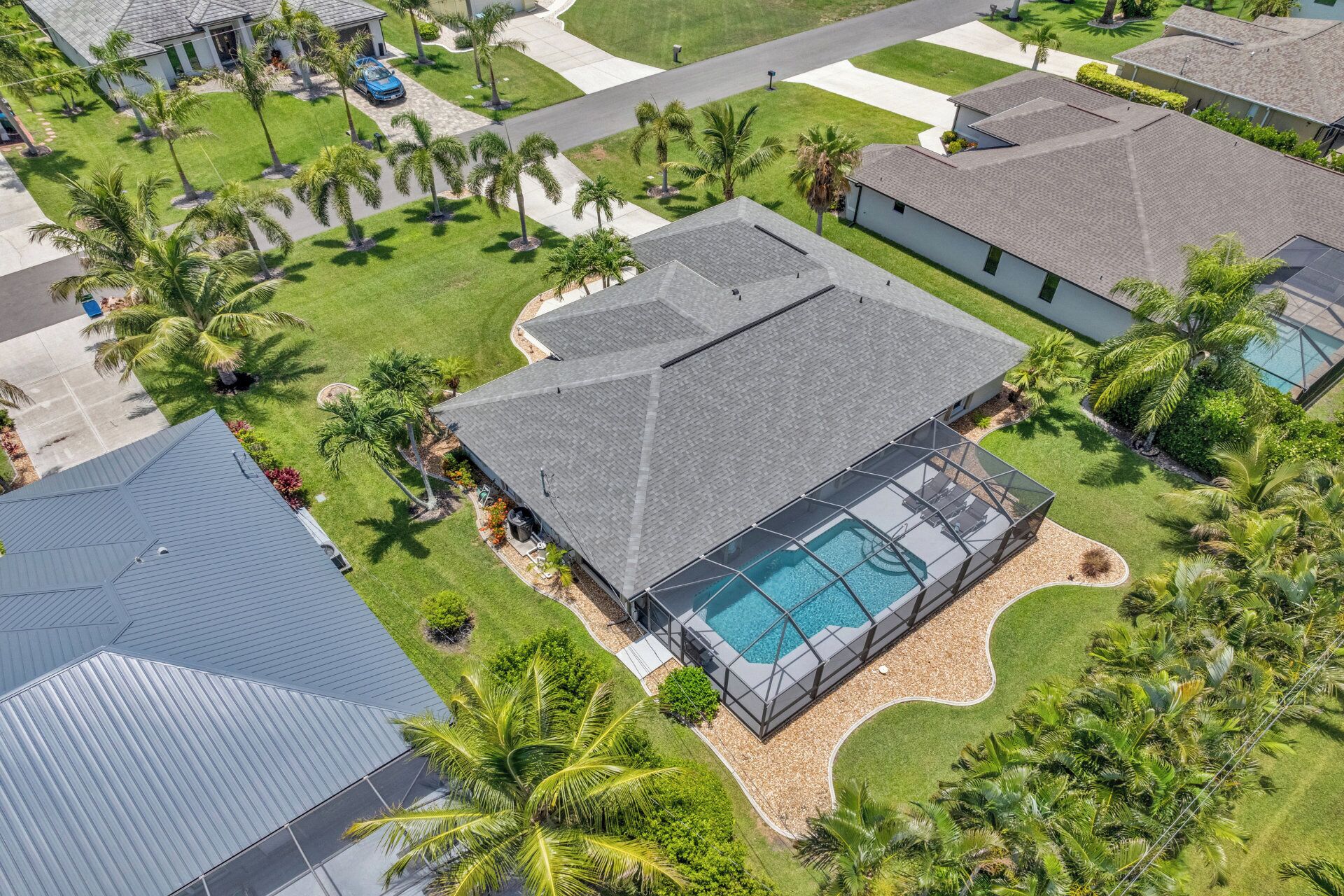 Vista aérea de un barrio residencial con casas, piscina y palmeras.
