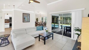 Ein geräumiger Wohnbereich mit einem weißen Sofa, einem Couchtisch und einem Deckenventilator.