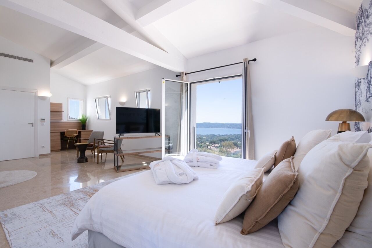 A modern hotel room with a large bed, a desk, and a TV.