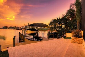 Um cais à beira-mar com barcos, uma área coberta e um calçadão pavimentado.