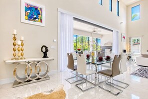 Uma sala de jantar moderna com mesa de vidro, cadeiras brancas e um aparador decorativo com uma escultura.