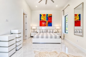 Un dormitorio moderno con una cama grande, dos mesitas de noche, una alfombra y pinturas abstractas en la pared.