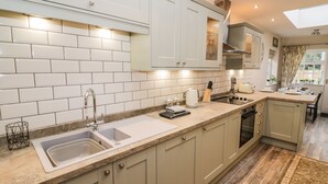 Una cocina moderna con azulejos blancos tipo metro, armarios color beige y una isla grande con fregadero.