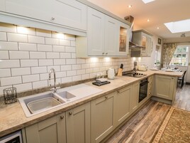 Una cocina moderna con azulejos blancos tipo metro, armarios color beige y una isla grande con fregadero.