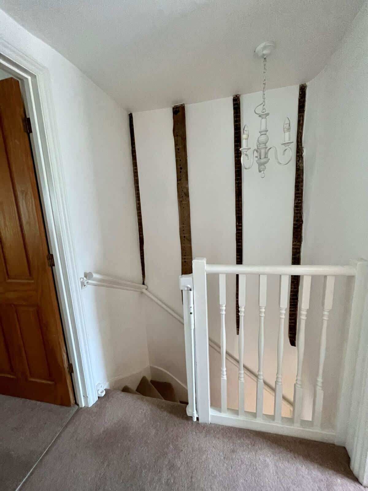 A staircase with a white railing, a wooden door, and a chandelier.