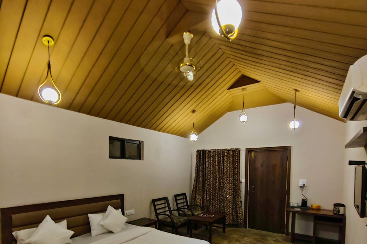Ein Schlafzimmer mit Holzboden, einem Bett mit weißer Bettwäsche, einem Schreibtisch mit Stuhl und einem kleinen Tisch mit Schüssel und Wasserkocher.