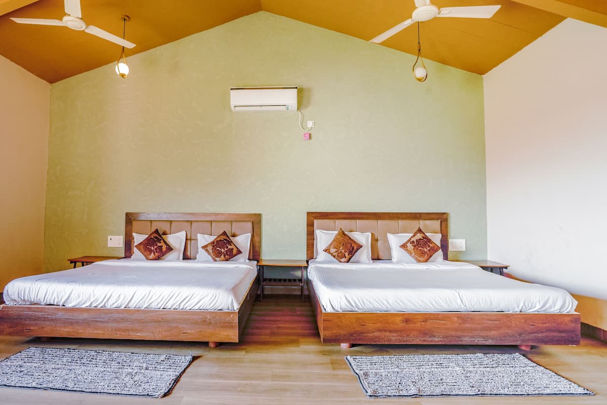 Ein Zimmer mit zwei Holzbetten, einem Deckenventilator, einer Klimaanlage und einem kleinen Tisch.