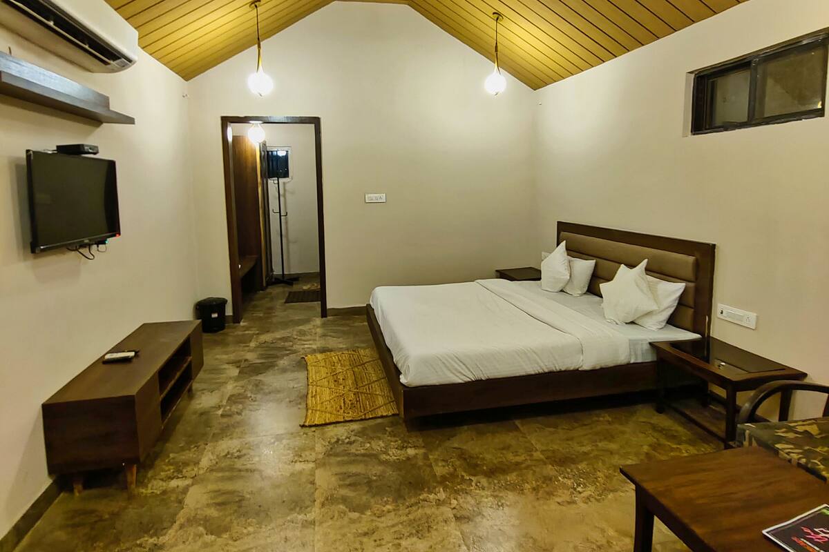 Ein Schlafzimmer mit schrägen Wänden, einem Bett, einem Fernseher und einem kleinen Tisch.