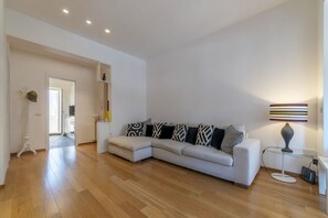 Ein modernes Wohnzimmer mit einem Ecksofa, einer Lampe und einem Bücherregal.