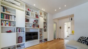 Una sala de estar moderna con una amplia estantería blanca, un televisor de pantalla plana y un sofá.