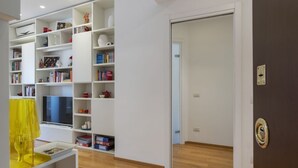 Una sala de estar moderna con televisor, estanterías y una lámpara amarilla.