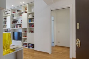 Un salon moderne avec un téléviseur, des étagères et une lampe jaune.