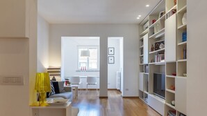 Una sala de estar moderna con un sofá, sillas, una mesa de centro y una estantería.