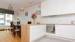 Una cocina moderna con armarios blancos, una isla de madera e iluminación colgante.