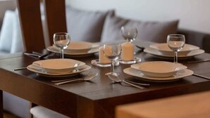 Una mesa de comedor dispuesta con platos, cubiertos y velas.