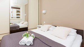Habitación de hotel con una cama grande, una mesita de noche, un espejo y vistas a un edificio por la ventana.