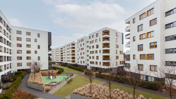 Complejo residencial con varios edificios de apartamentos, un patio central con área de juegos y zonas ajardinadas.