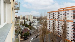 Un edificio residencial alto con varios balcones, un área de estacionamiento y vistas despejadas de los edificios circundantes.