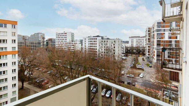 Vista de una zona residencial con varios edificios de apartamentos, un estacionamiento y árboles sin hojas.