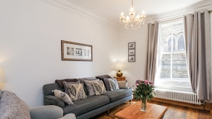 Ein modernes Wohnzimmer mit einem grauen Sofa, einem Holztisch und einer Kronleuchter.