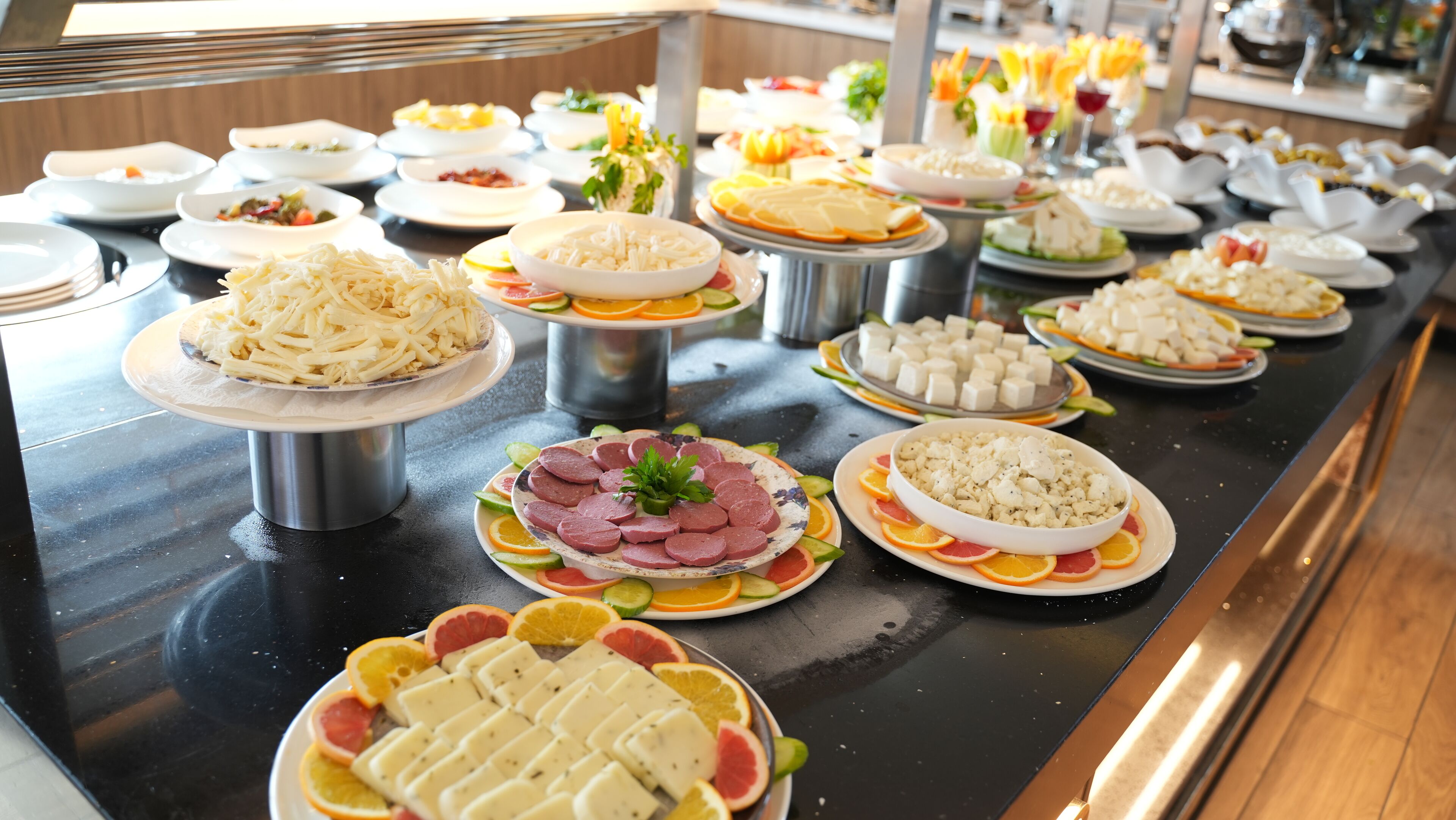 Un buffet proposant une variété de plats, notamment des fromages, des viandes et des fruits.
