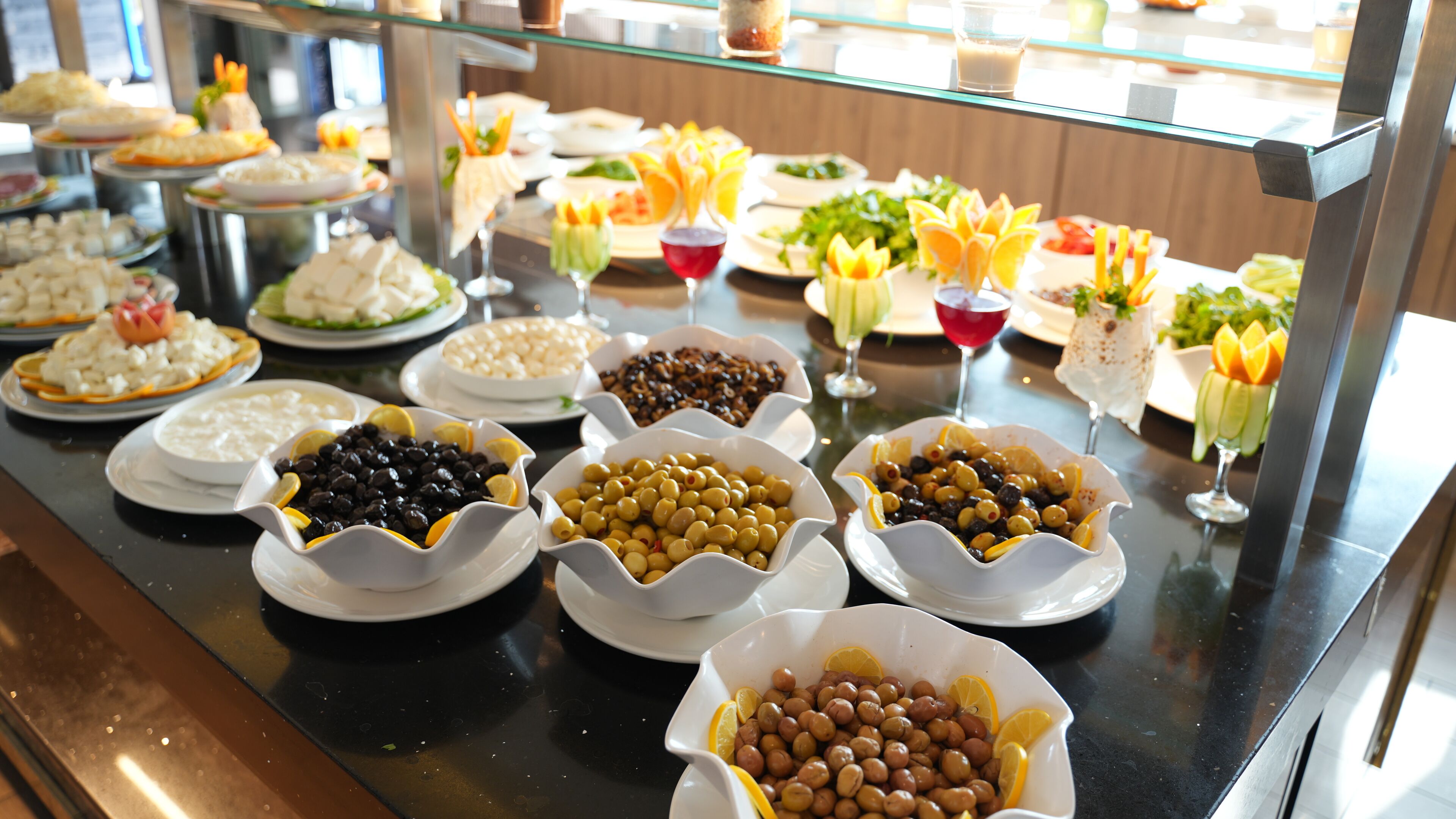 A buffet with various dishes including olives, nuts, and fruits.