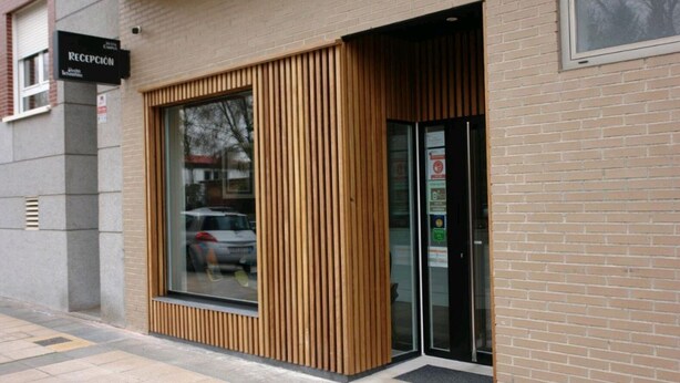 A reception area with a large window and a wooden slatted design. - Hostel Trovadores (Burgos)