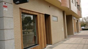 A modern building with a large window and wooden slats, a sign for 'Alarma', and a brick facade. - Hostel Trovadores (Burgos)