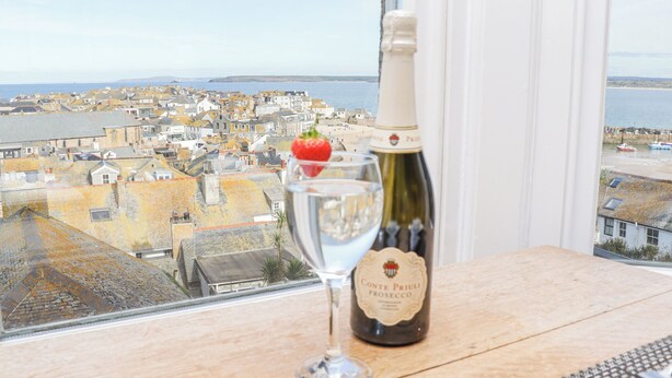 A bottle of wine and a glass on a table with a view of a coastal town. - Whistler (St Ives)